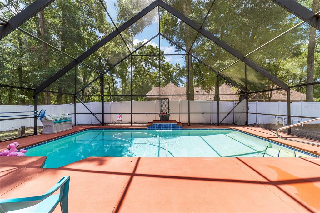A living room with wood-paneled vaulted ceilings, light wood flooring, and patterned red furniture — 5300 NE 2ND LANE, OCALA, FL