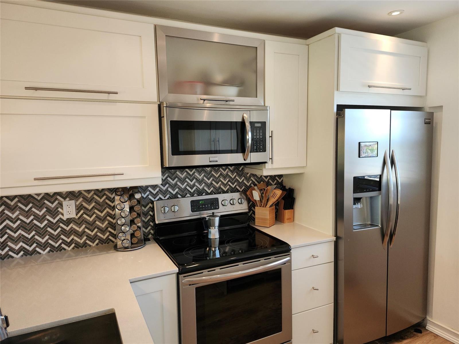 A kitchen features white cabinets, stainless steel appliances, and a chevron-patterned tile backsplash — 301 Cambridge Road # 301, Hollywood FL 33024, HOLLYWOOD, FL