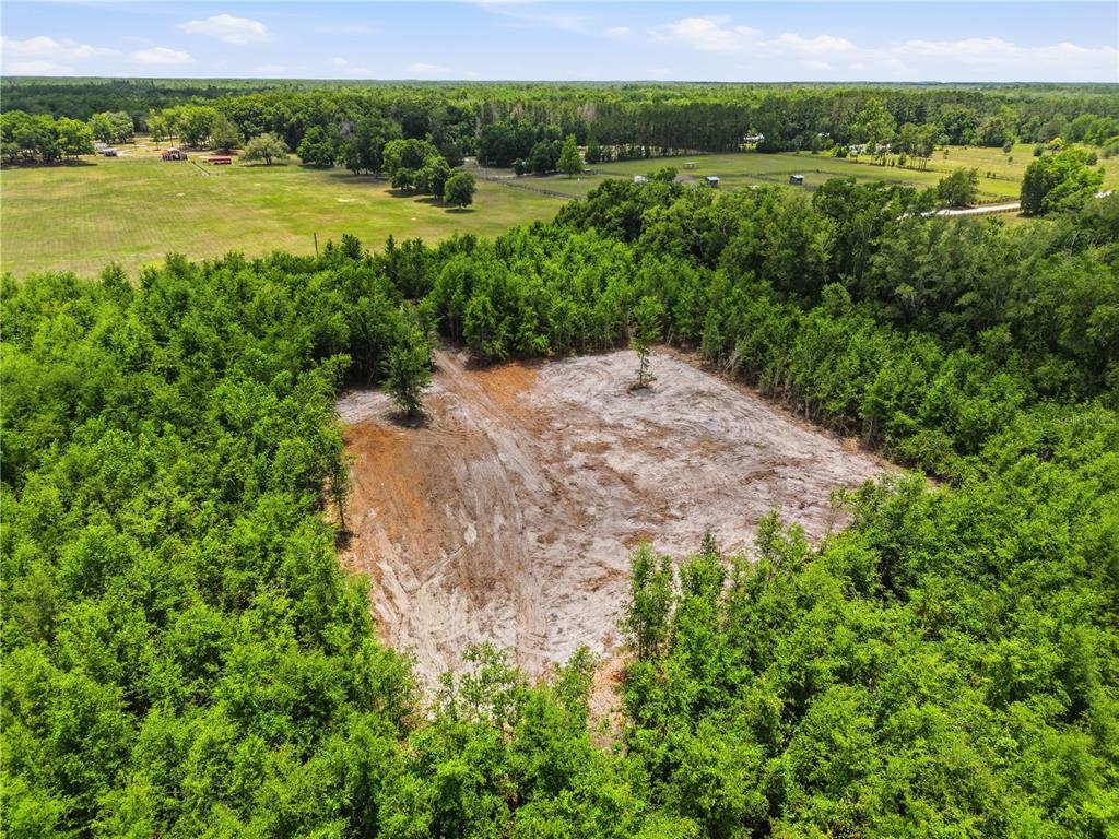 An aerial view shows a cleared, sandy lot surrounded by dense green forest — SW 188TH ST, ARCHER, FL