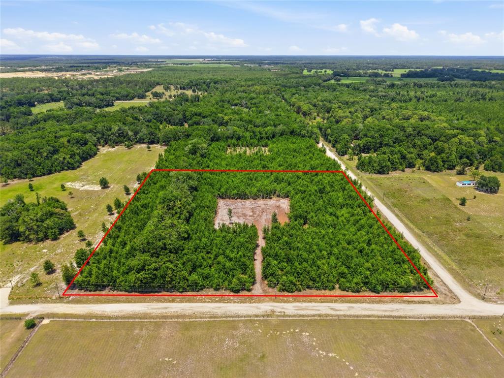 An aerial view shows a rectangular, wooded lot with a cleared building site and driveway — SW 188TH ST, ARCHER, FL