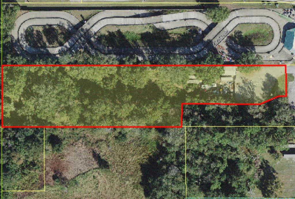 An aerial view shows a rectangular plot of land outlined in red near a track — 4708 W IRLO BRONSON MEMORIAL HIGHWAY, KISSIMMEE, FL
