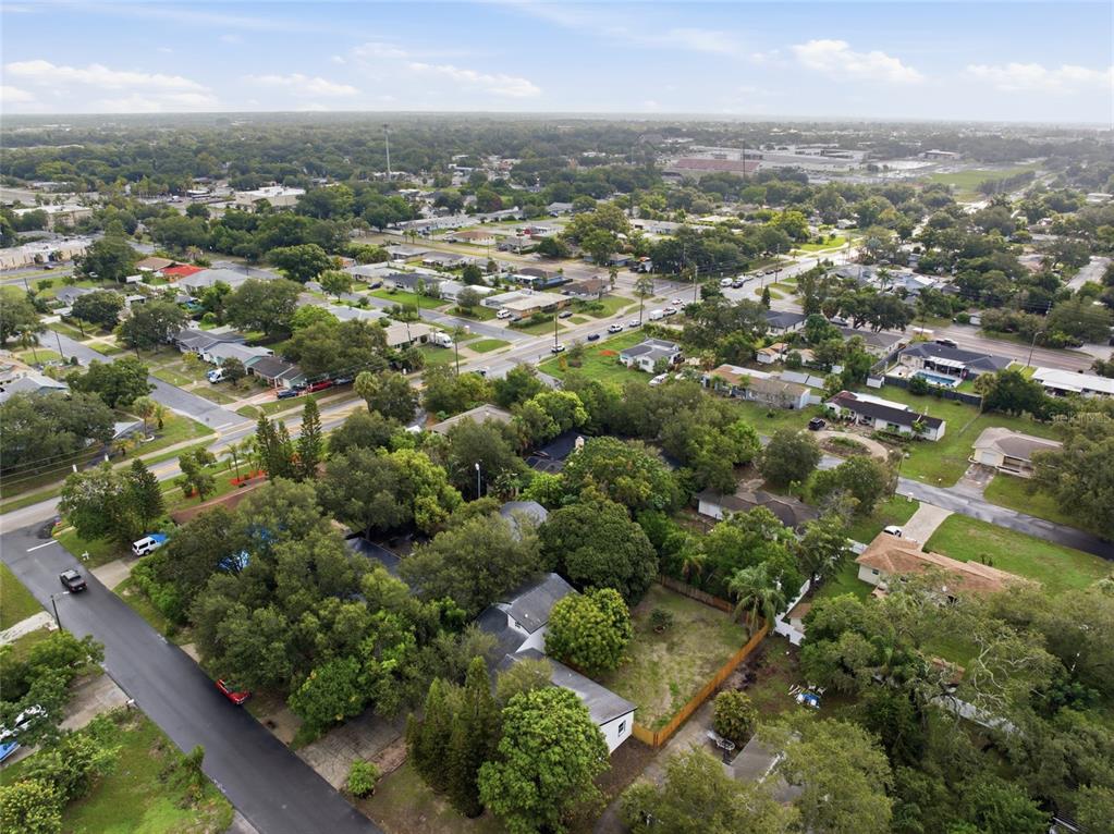 An aerial view shows a residential neighborhood with houses, tree-lined streets, and surrounding green space — 809 WOODCREST AVENUE, CLEARWATER, FL