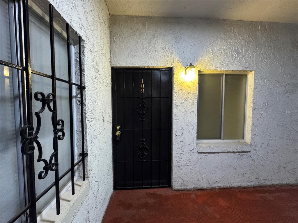 A black metal security door and window grate are installed on a white stucco exterior wall — 4575 S TEXAS AVENUE UNIT 109, ORLANDO, FL