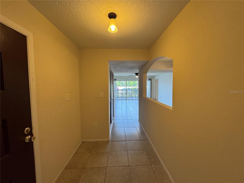 A tiled entryway leads to a hallway with a cutout wall overlooking a sunlit room — 4575 S TEXAS AVENUE UNIT 109, ORLANDO, FL