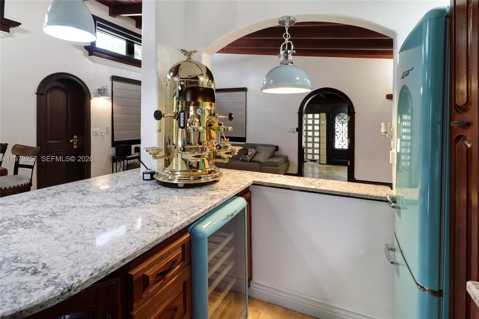 A kitchen features a gold espresso machine, granite countertops, and a retro-style turquoise refrigerator — 550 Quail Ave, Miami Springs FL 33166, MIAMI SPRINGS, FL