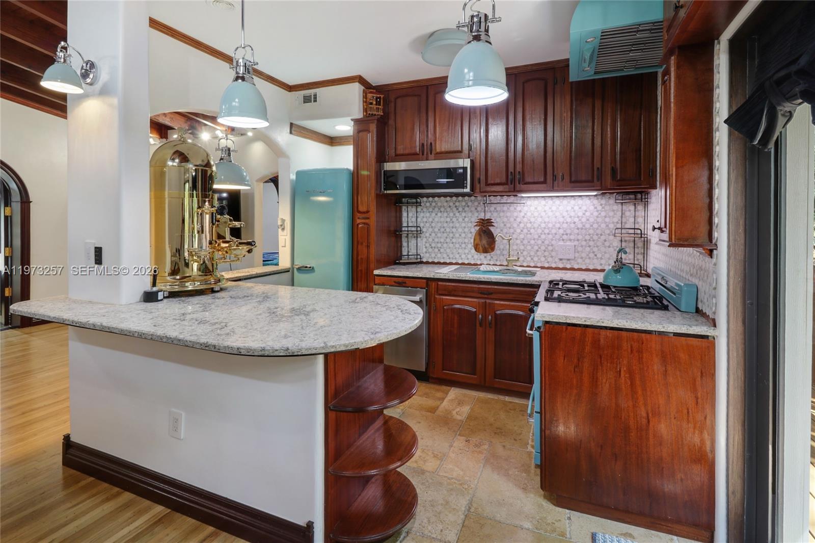 A kitchen features dark wood cabinets, a light granite countertop, and a retro blue refrigerator — 550 Quail Ave, Miami Springs FL 33166, MIAMI SPRINGS, FL