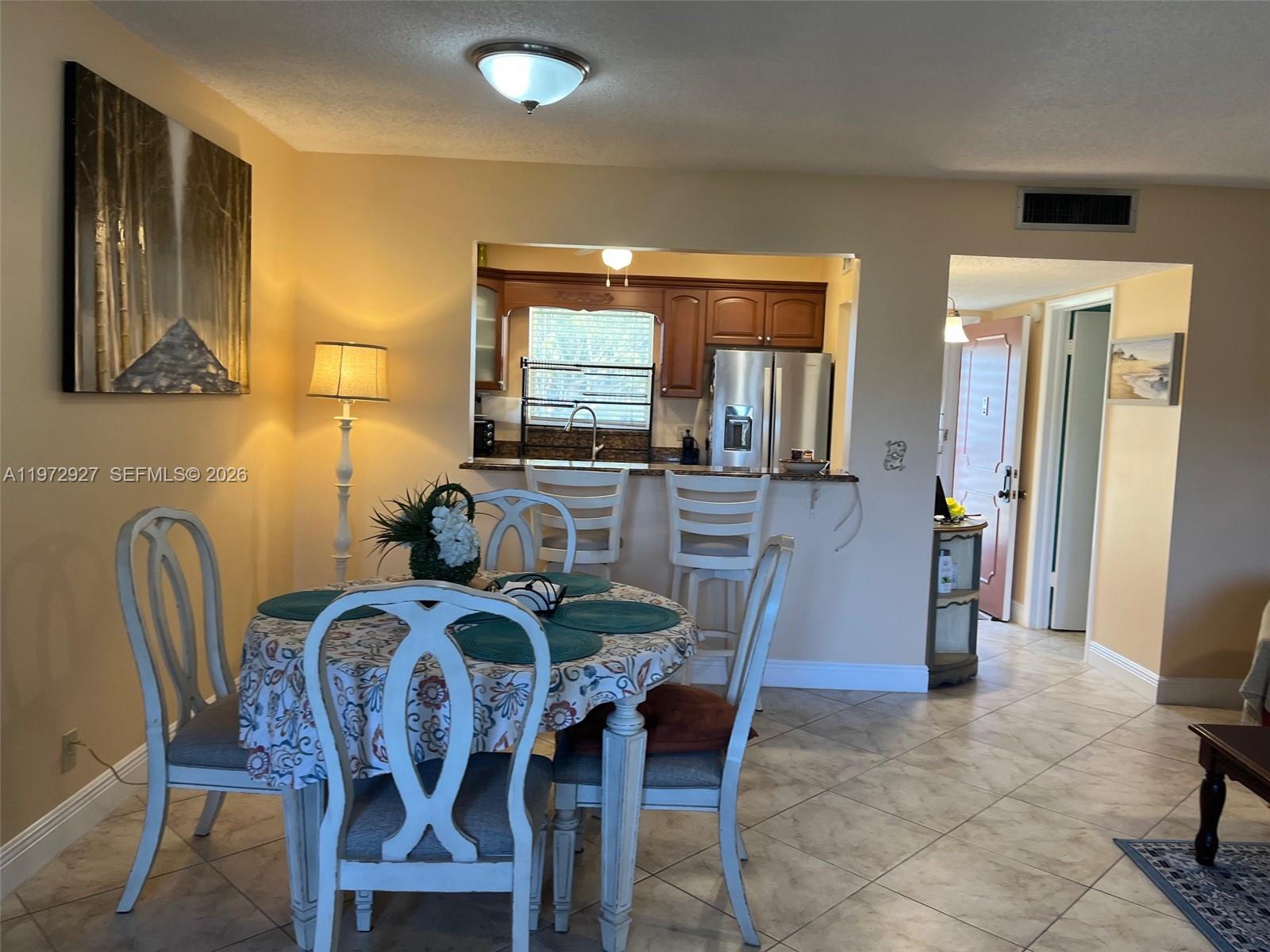 A dining area with a round table sits in front of an open kitchen pass-through — 752 Lori Dr # 218, Palm Springs FL 33461, PALM SPRINGS, FL