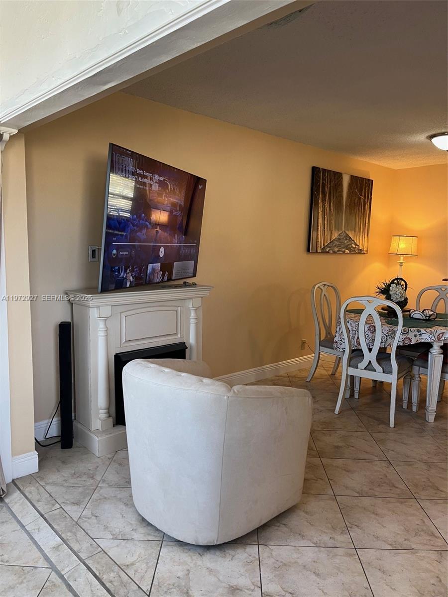 A living room features a fireplace with a mounted television, a white armchair, and a dining area — 752 Lori Dr # 218, Palm Springs FL 33461, PALM SPRINGS, FL