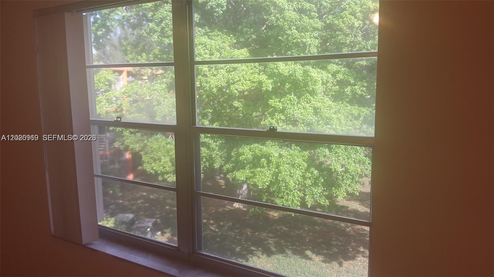 A view of green trees through a large, multi-pane window in a room — 4384 NW 9th Ave # 3B, Deerfield Beach FL 33064, DEERFIELD BEACH, FL