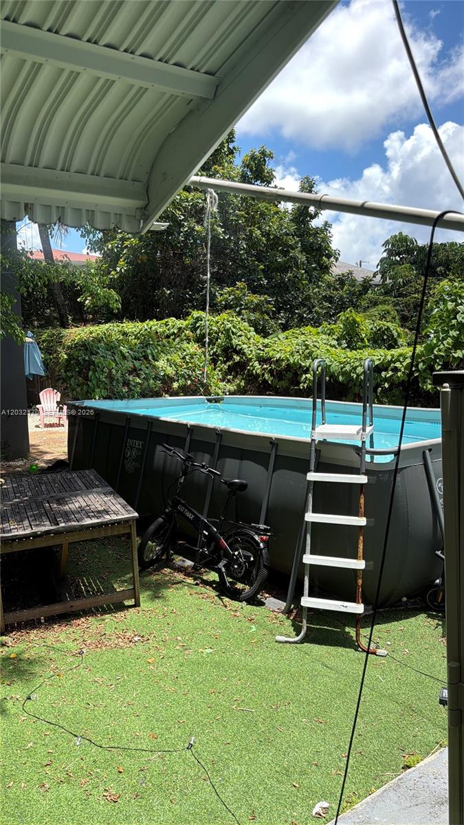 An above-ground swimming pool with a ladder sits in a backyard with a bicycle — 843 NW 3rd St # 2, Miami FL 33128, MIAMI, FL