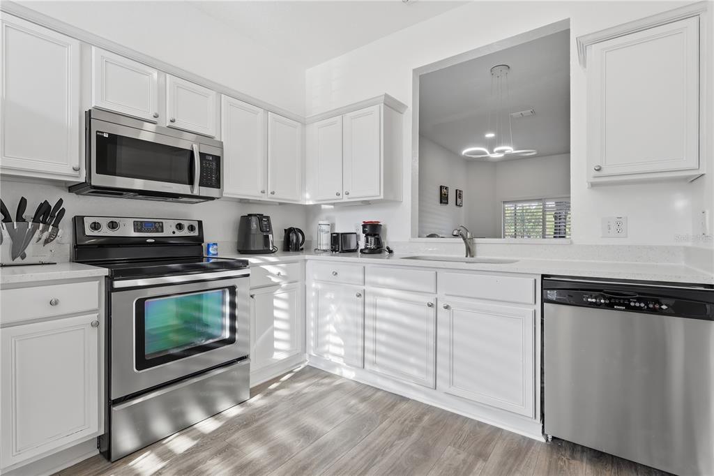 A kitchen with white cabinets, stainless steel appliances, and light wood-look flooring — 3438 CALABRIA AVENUE UNIT 3438, DAVENPORT, FL