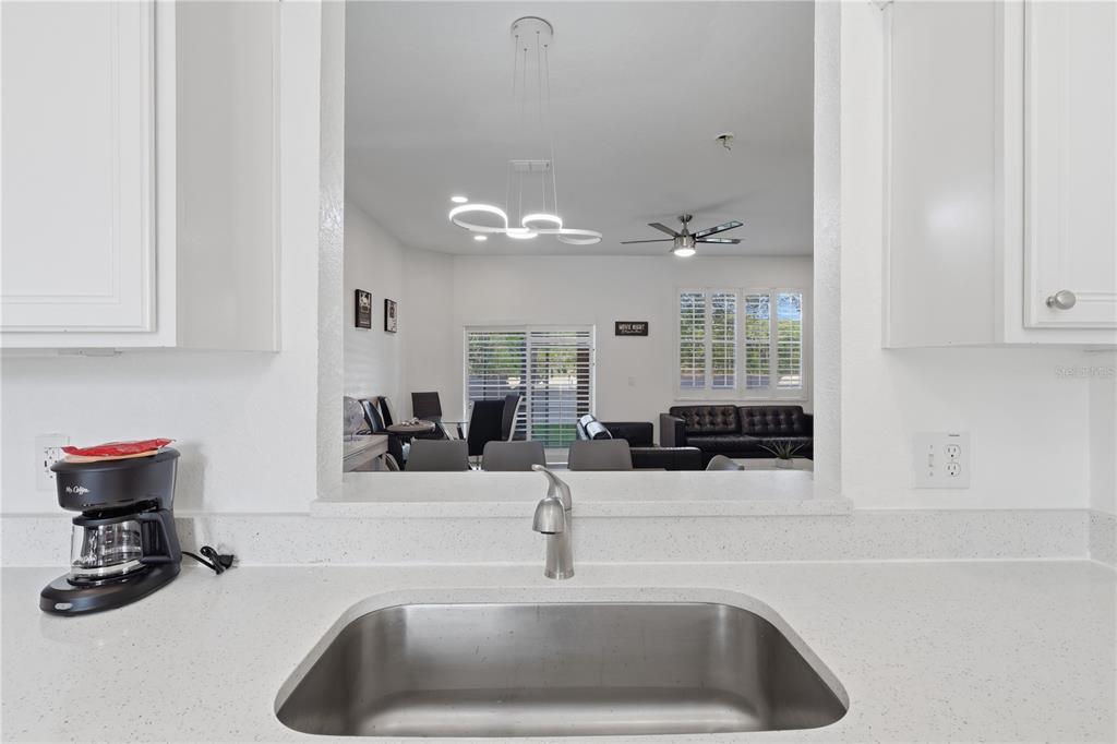 A kitchen sink and countertop look through a pass-through window into a living area — 3438 CALABRIA AVENUE UNIT 3438, DAVENPORT, FL