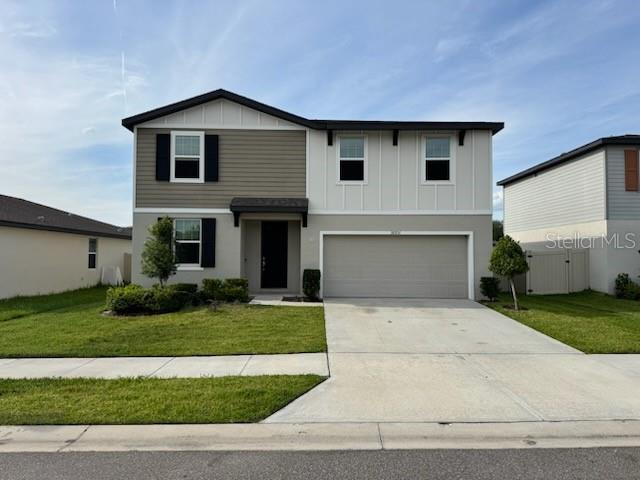 A two-story suburban house features a two-car garage, light-colored siding, and a small front lawn — 38851 OPAL WILLOW LANE, ZEPHYRHILLS, FL