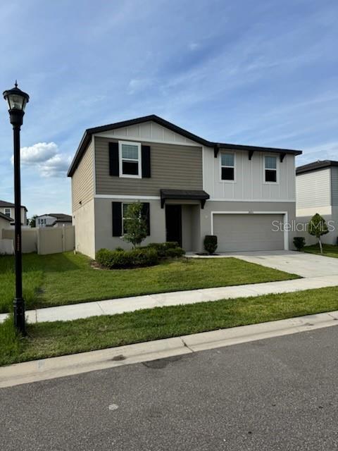 A two-story suburban house features beige siding, a two-car garage, and a front lawn — 38851 OPAL WILLOW LANE, ZEPHYRHILLS, FL
