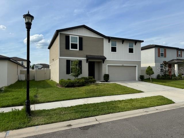 A two-story suburban house features tan and white siding with a front-facing garage — 38851 OPAL WILLOW LANE, ZEPHYRHILLS, FL
