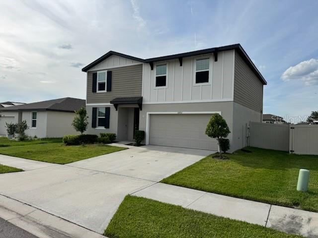 A two-story suburban house features a gray garage, white siding, and a manicured lawn — 38851 OPAL WILLOW LANE, ZEPHYRHILLS, FL