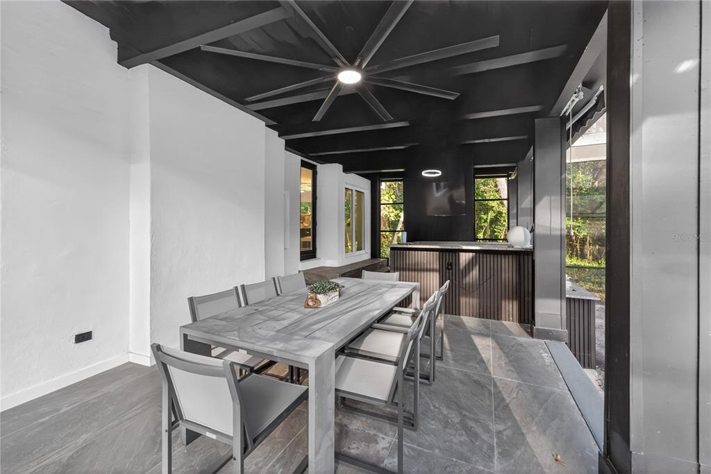 A covered outdoor patio features a dining table, a bar area, and dark ceiling beams — 305 SWEETWATER CLUB CIRCLE, LONGWOOD, FL