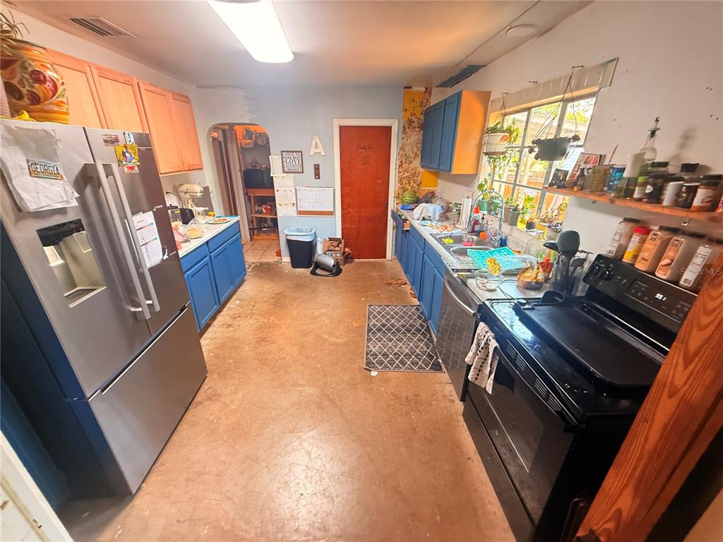 A kitchen features blue and wood-toned cabinets, stainless steel appliances, and a concrete floor — 714 26TH STREET W, BRADENTON, FL