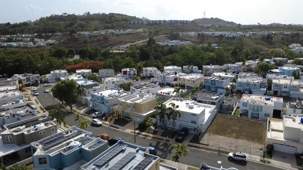 An aerial view shows a suburban neighborhood with modern houses, flat roofs, and solar panels — 3 SE . UNIT PG 133, TRUJILLO ALTO, PR