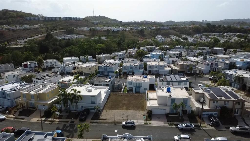An aerial view shows a vacant residential lot situated between two houses in a suburban neighborhood — 3 SE . UNIT PG 133, TRUJILLO ALTO, PR