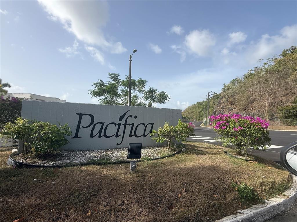 A gray concrete sign with the word Pacifica stands near a road and landscaping — 3 SE . UNIT PG 133, TRUJILLO ALTO, PR