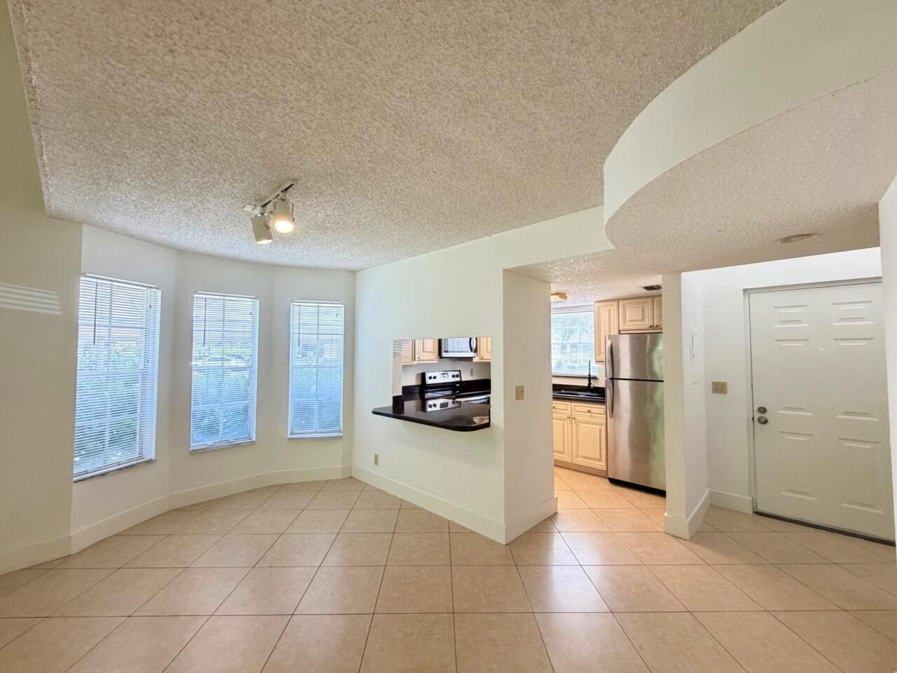 A dining area with tile floors and a pass-through window looking into the kitchen — 6308 La Costa Drive # D, Boca Raton FL 33433, BOCA RATON, FL