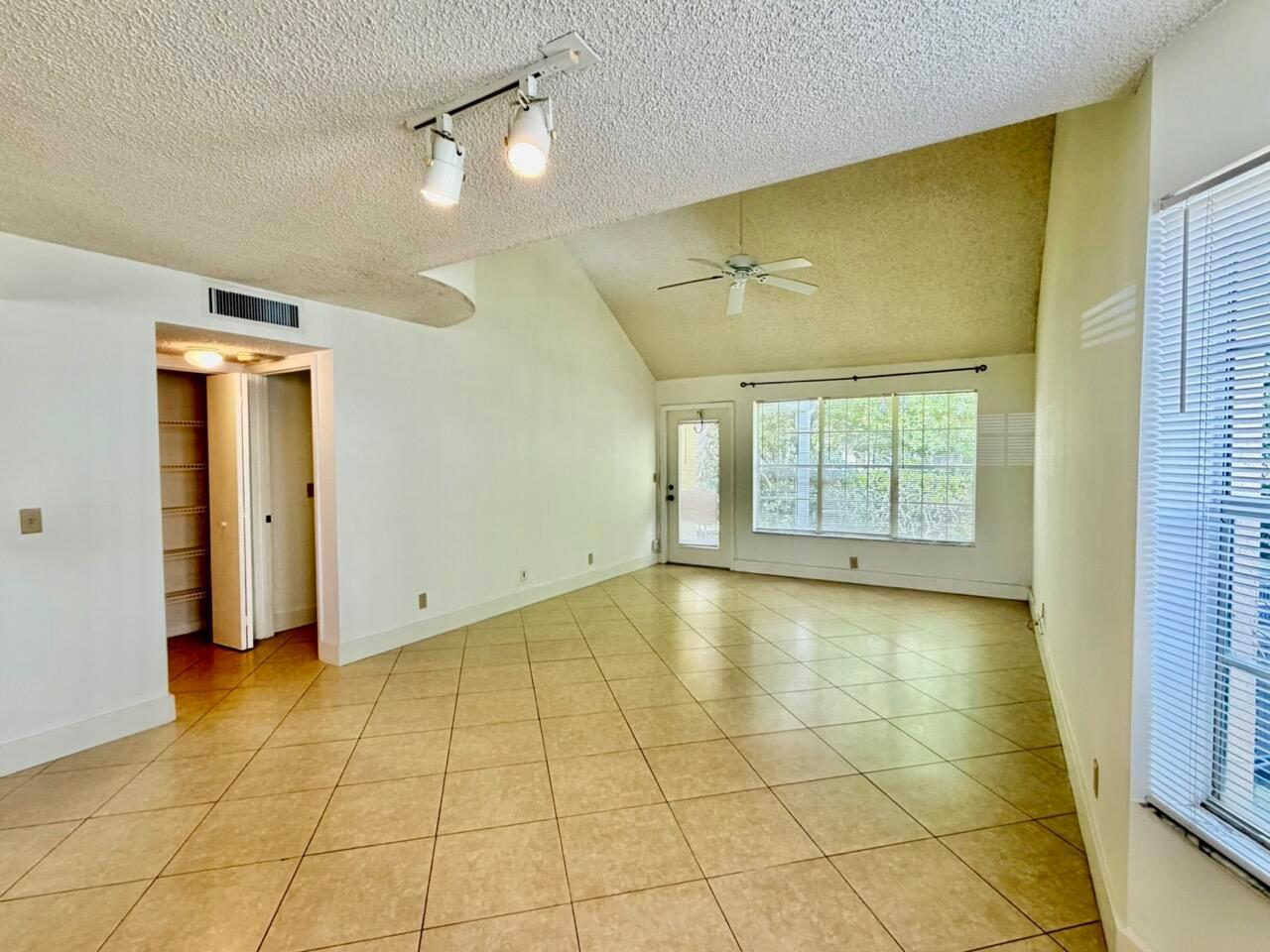 A living room with vaulted ceilings, tile flooring, a ceiling fan, and a glass door — 6308 La Costa Drive # D, Boca Raton FL 33433, BOCA RATON, FL
