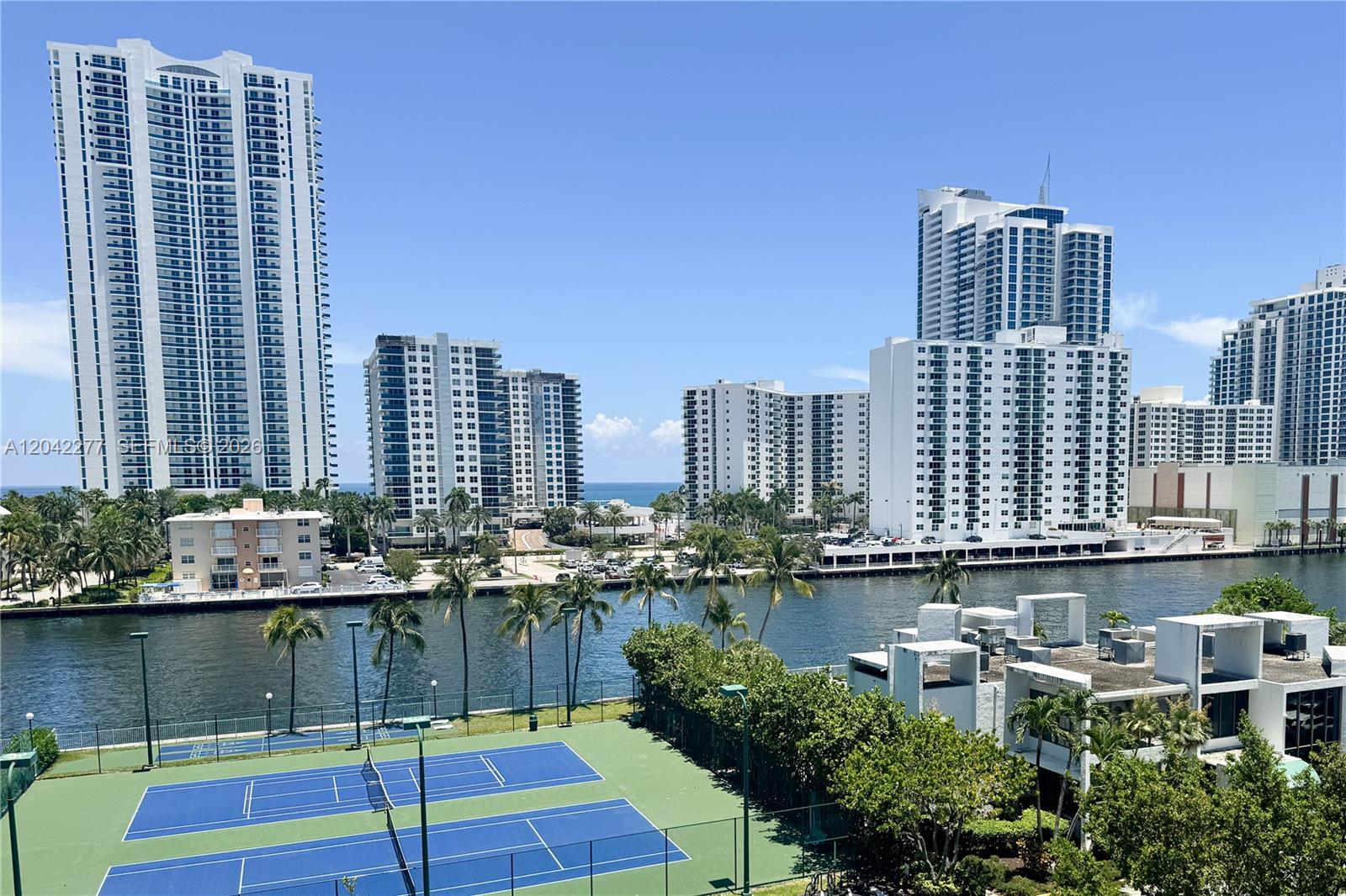 An elevated view of a tennis court, a canal, and several high-rise apartment buildings — 1000 Parkview Dr # 726, Hallandale Beach FL 33009, HALLANDALE BEACH, FL