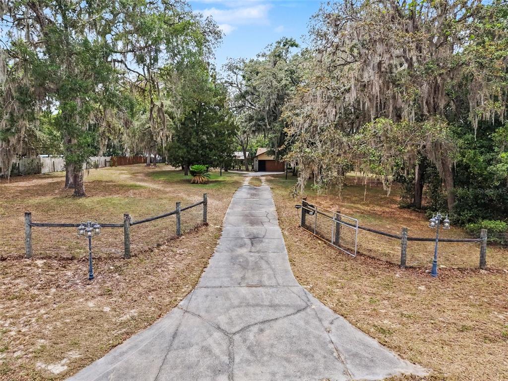 A single-story house with a tan stucco exterior, stone accents, and a brown shingled roof — 7111 RICKER AVENUE, WEBSTER, FL