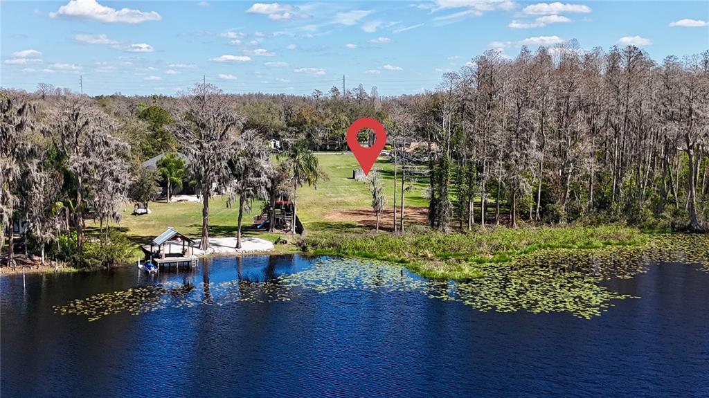 An aerial view shows a grassy waterfront lot with a boat dock and trees — BLOUNT ROAD, LUTZ, FL
