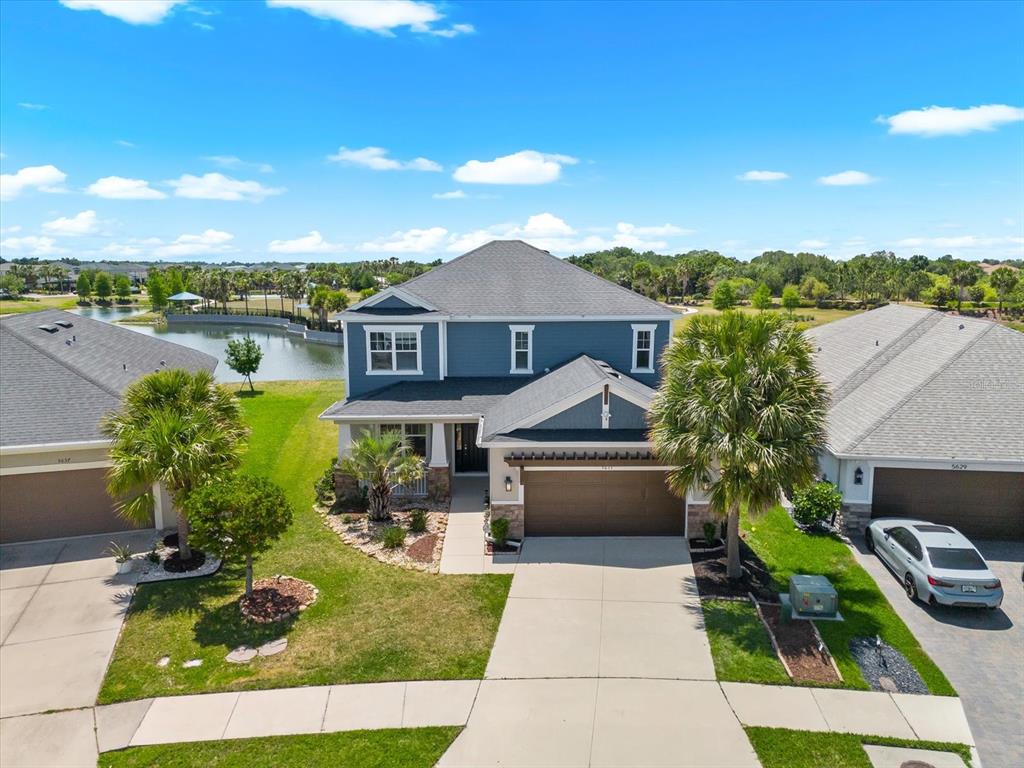 An aerial view of a two-story blue house with a garage and a nearby pond — 5633 MAIDENSTONE WAY, PALMETTO, FL