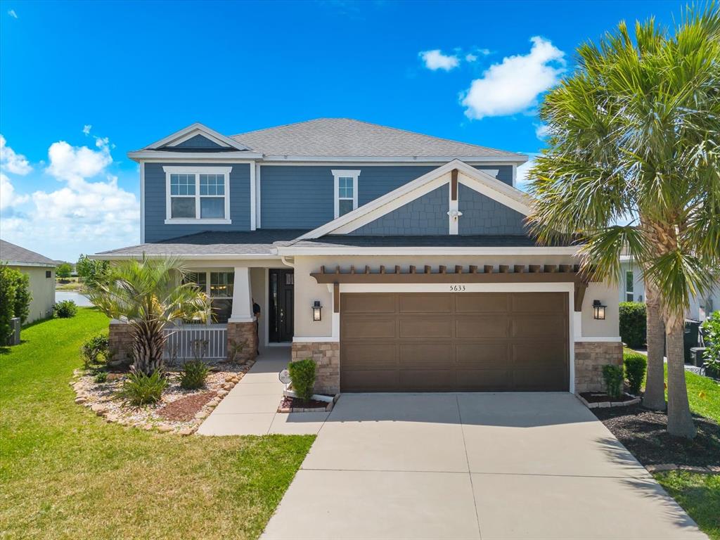 A two-story house features blue siding, a brown garage door, and a stone-accented front porch — 5633 MAIDENSTONE WAY, PALMETTO, FL