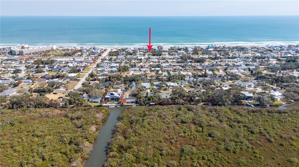 An aerial view shows a coastal neighborhood with a red arrow pointing toward a house — 4609 S ATLANTIC AVENUE, NEW SMYRNA BEACH, FL