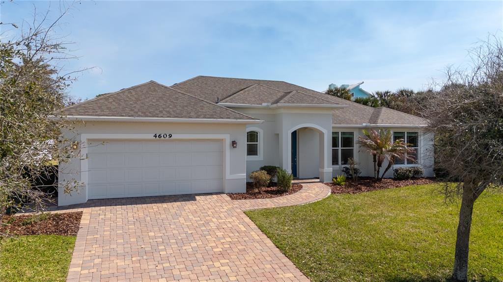 A single-story house with a beige stucco exterior, a two-car garage, and a paver driveway — 4609 S ATLANTIC AVENUE, NEW SMYRNA BEACH, FL