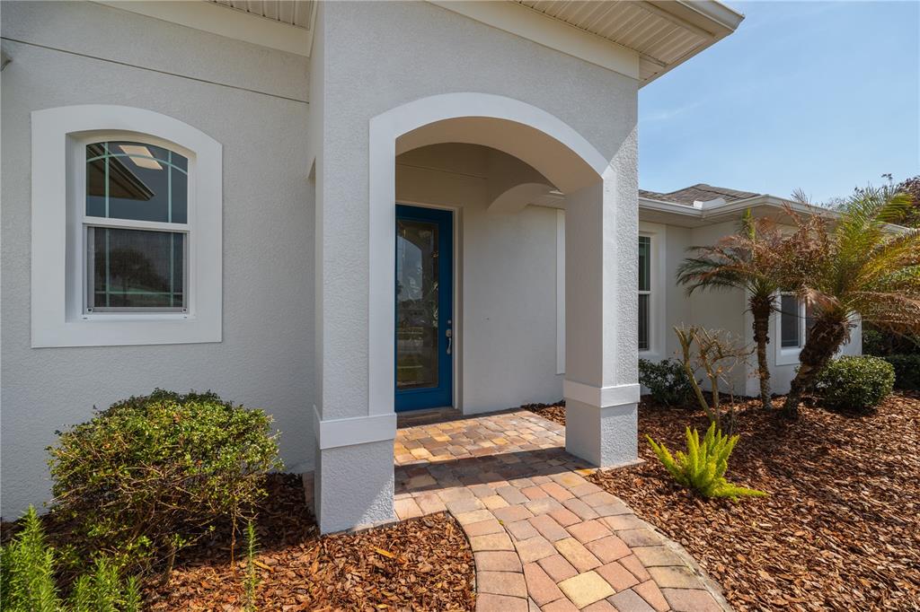 A paved walkway leads to the blue front door of a house with stucco siding — 4609 S ATLANTIC AVENUE, NEW SMYRNA BEACH, FL