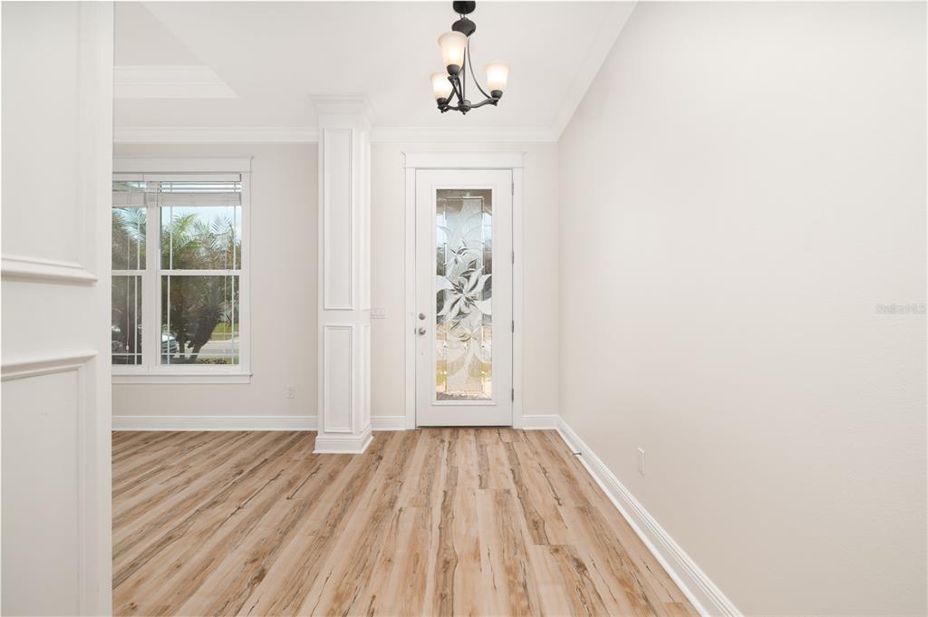 An entryway features light wood-look flooring, a white pillar, and a glass-paneled front door — 4609 S ATLANTIC AVENUE, NEW SMYRNA BEACH, FL