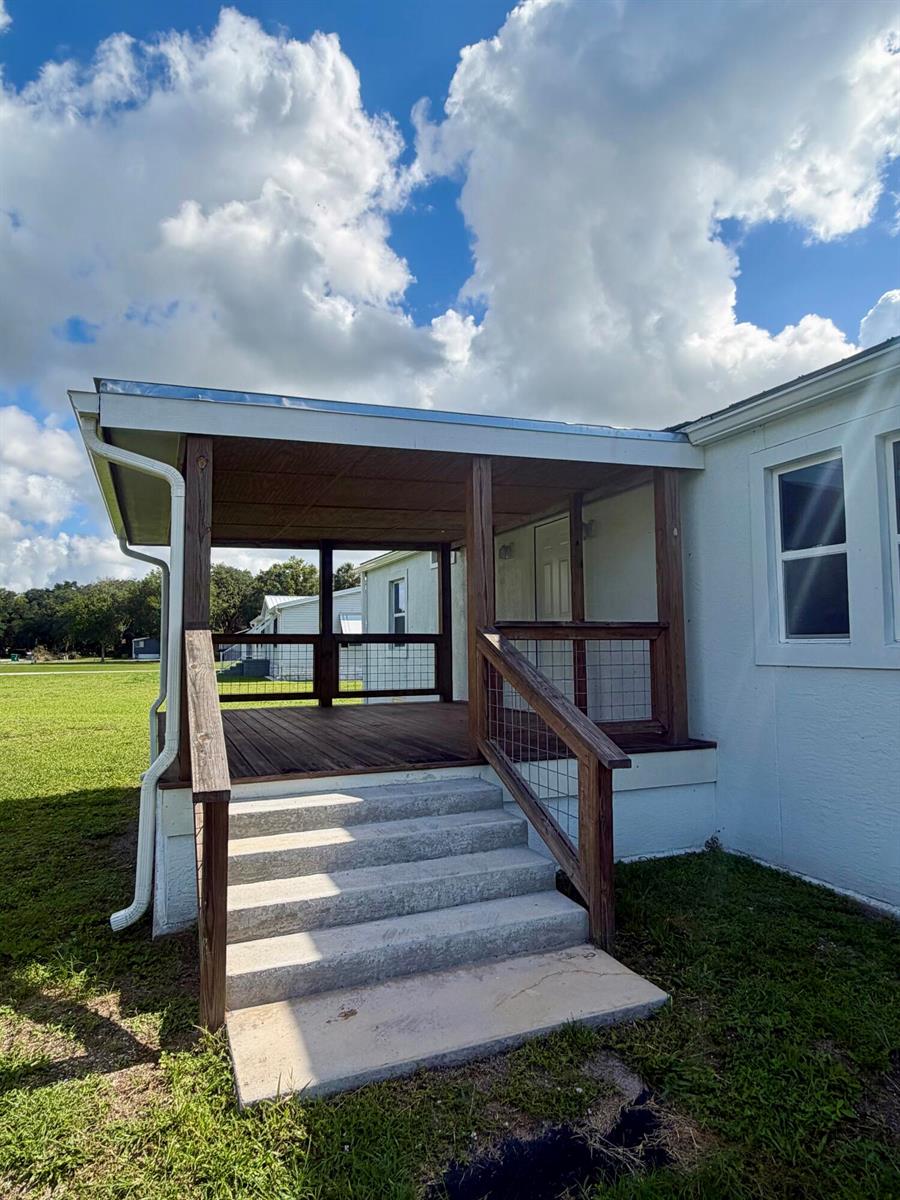 A covered wooden porch with wire railings and concrete steps attached to a white house — 2822 SE 47th Terrace, Okeechobee FL 34974, OKEECHOBEE, FL