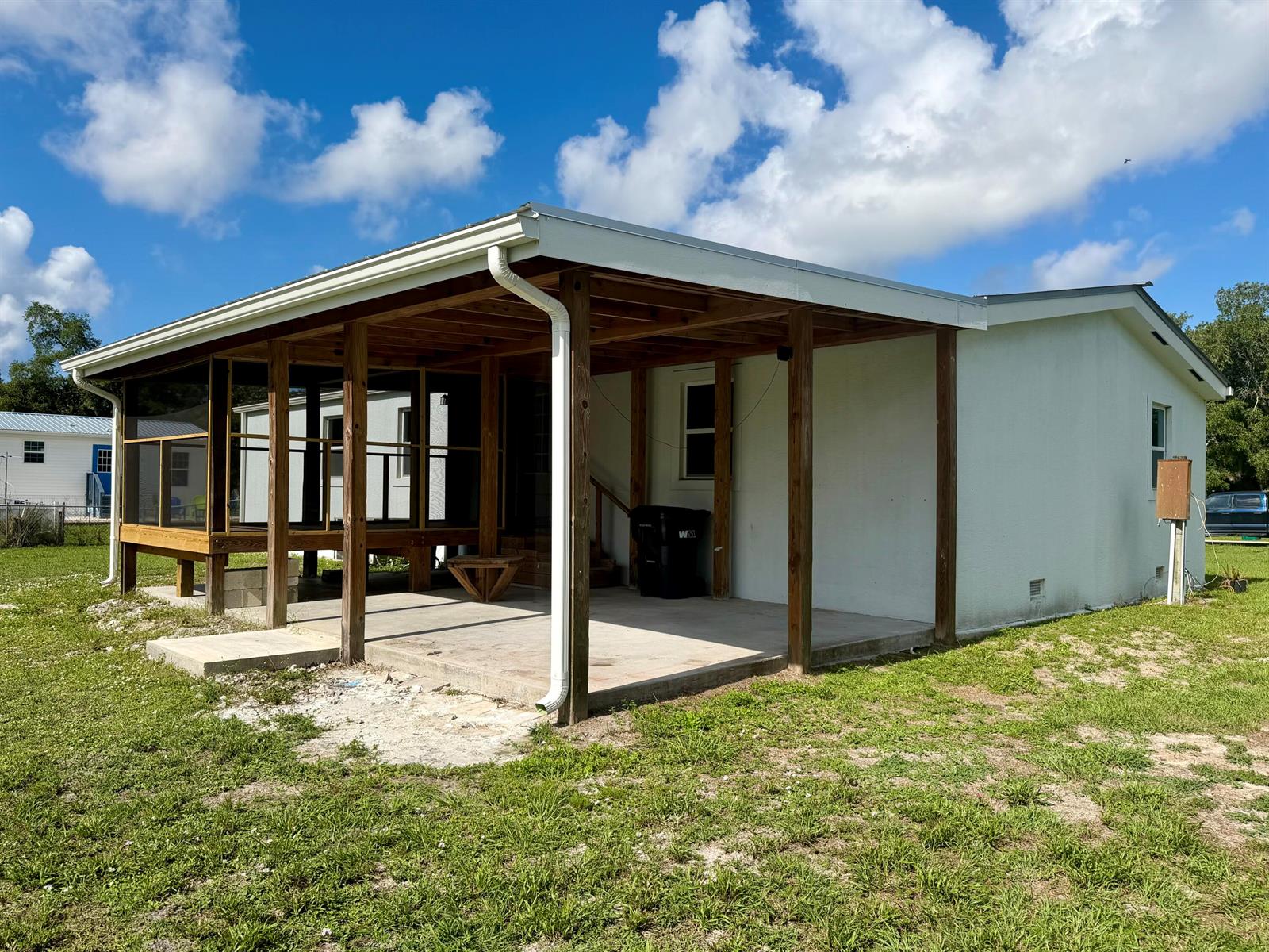 A white house features a large covered concrete patio and an attached screened-in porch area — 2822 SE 47th Terrace, Okeechobee FL 34974, OKEECHOBEE, FL