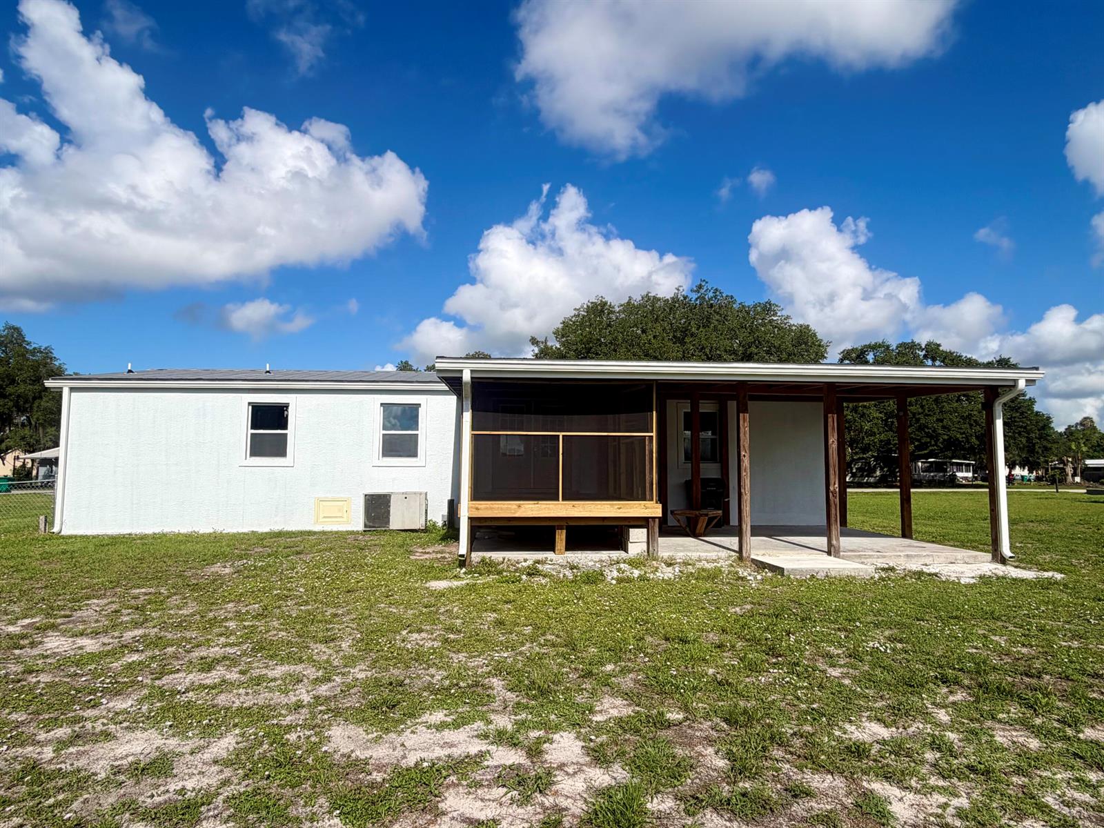 A white house with a screened-in porch and a covered patio sits on a lawn — 2822 SE 47th Terrace, Okeechobee FL 34974, OKEECHOBEE, FL