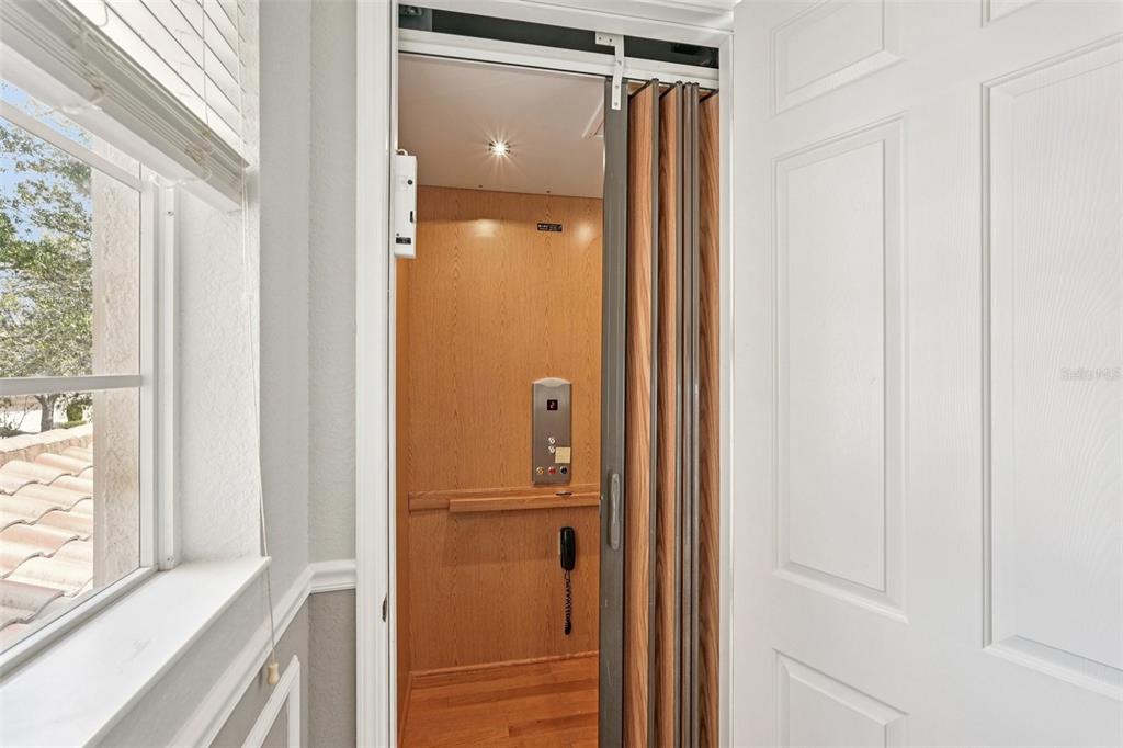 An elevator with wood paneling and a folding door is situated inside a residential home — 1435 EMERALD DUNES DRIVE, SUN CITY CENTER, FL