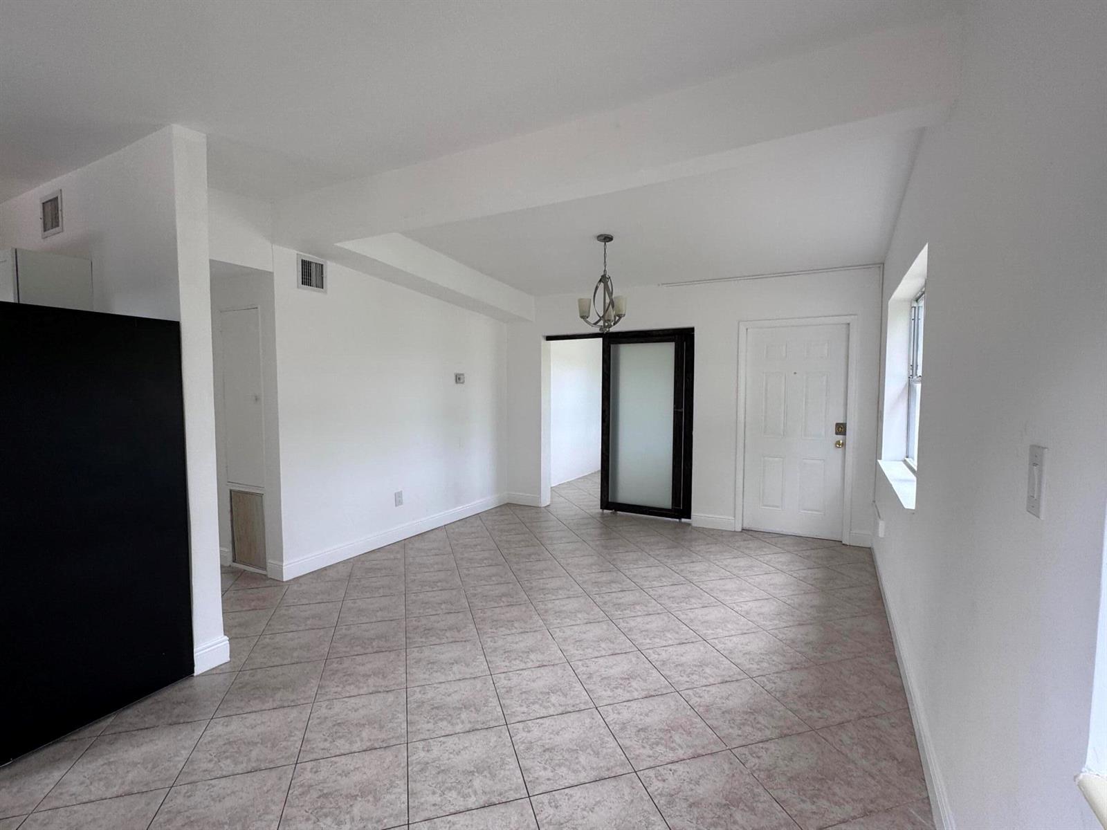 An empty room with tiled floors, a white door, and a frosted glass sliding door — 4310 NE 13th Avenue, Pompano Beach FL 33064, POMPANO BEACH, FL