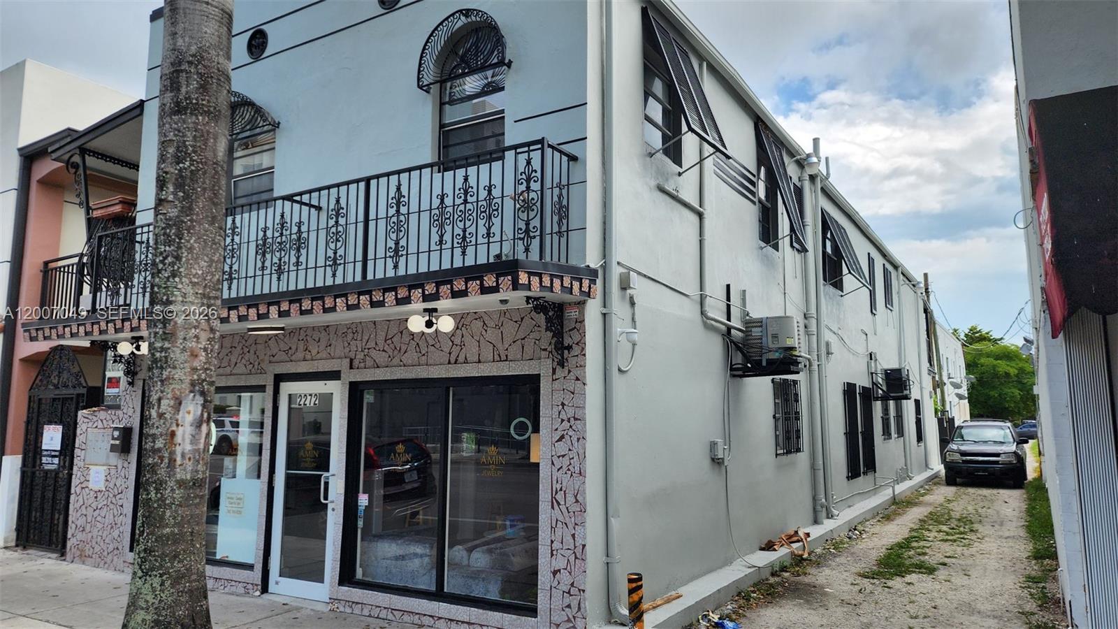A two-story building with a stone-tiled storefront, a black metal balcony, and a side alley — 2272 SW 8th St # 3, Miami FL 33135, MIAMI, FL