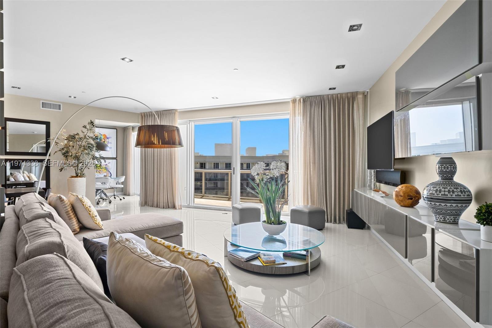 A modern living room features a large sectional sofa, glass coffee table, and balcony access — 9601 Collins Ave # 1208, Bal Harbour FL 33154, BAL HARBOUR, FL