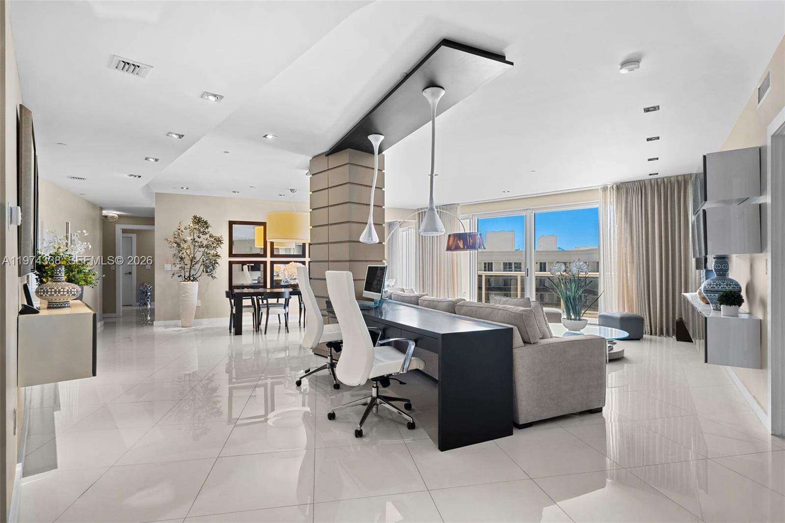 A modern living room features a desk behind a sofa, tile floors, and large windows — 9601 Collins Ave # 1208, Bal Harbour FL 33154, BAL HARBOUR, FL