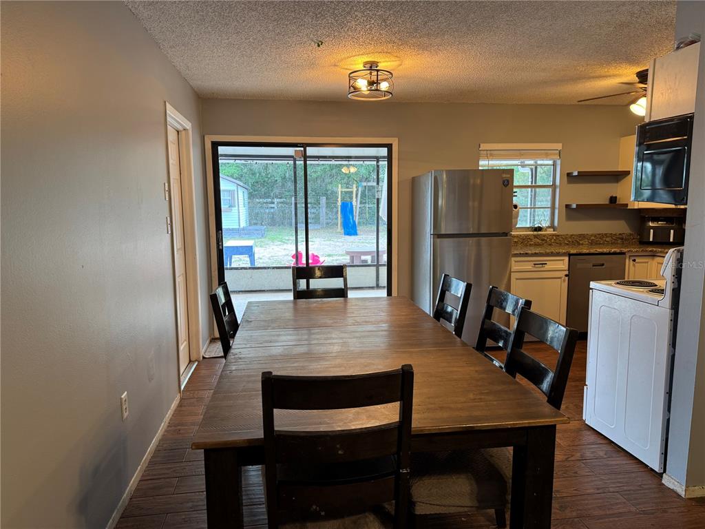A dining room with a wooden table, chairs, stainless steel refrigerator, and sliding glass doors — 580 FERN AVENUE, TAVARES, FL