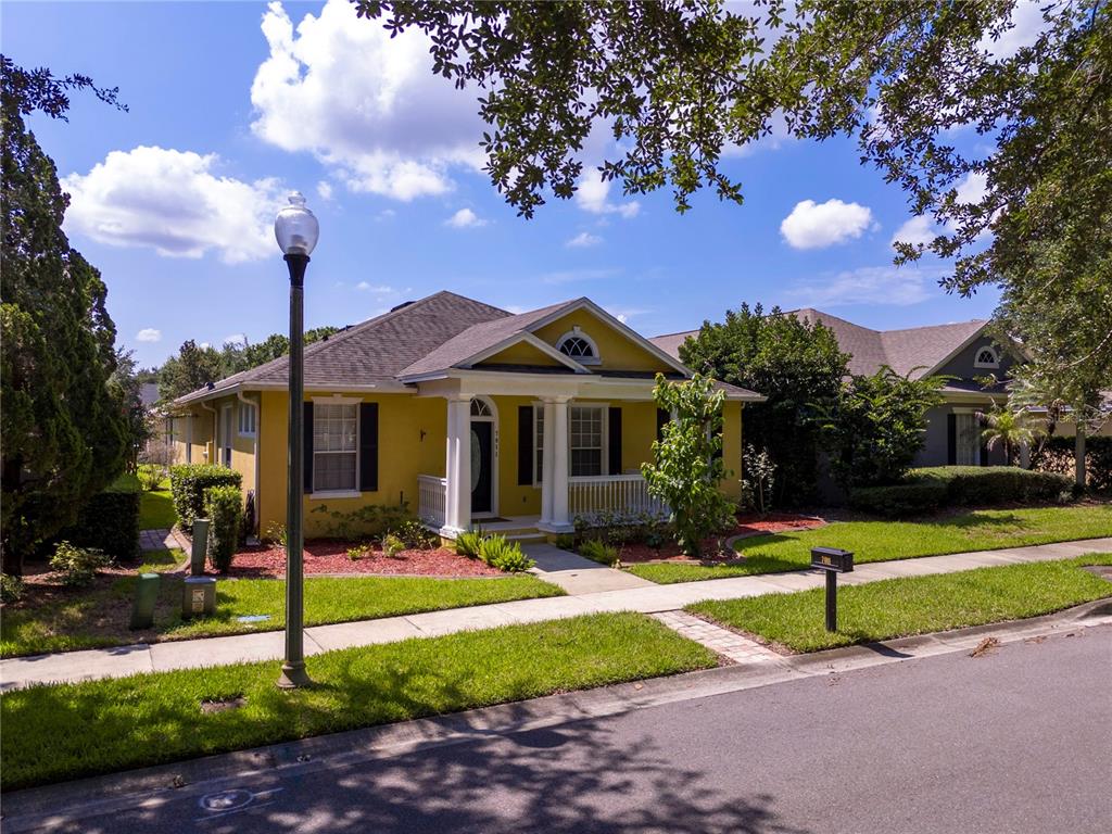 A yellow single-story house with a front porch and white columns sits on a lawn — 7011 NOBLETON DRIVE, WINDERMERE, FL
