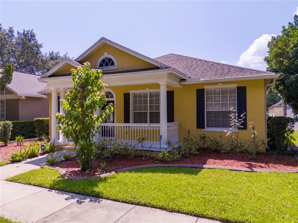 A yellow single-story house features a front porch with white columns and black shutters — 7011 NOBLETON DRIVE, WINDERMERE, FL
