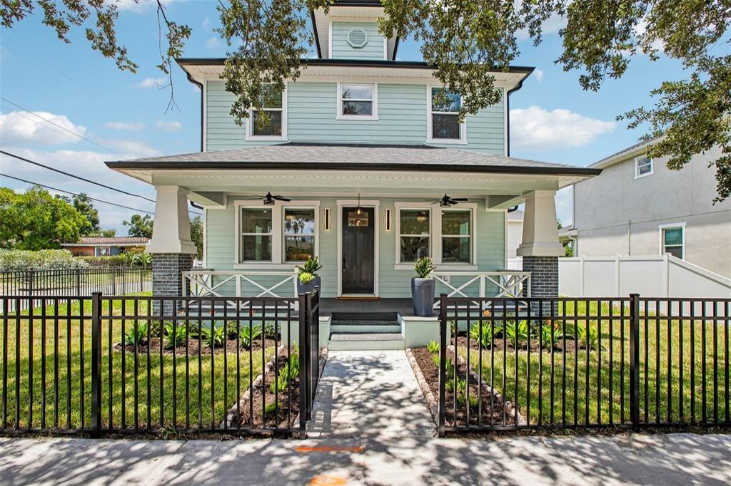 A light blue two-story house with a front porch and black metal fence — 406 E CHELSEA STREET, TAMPA, FL