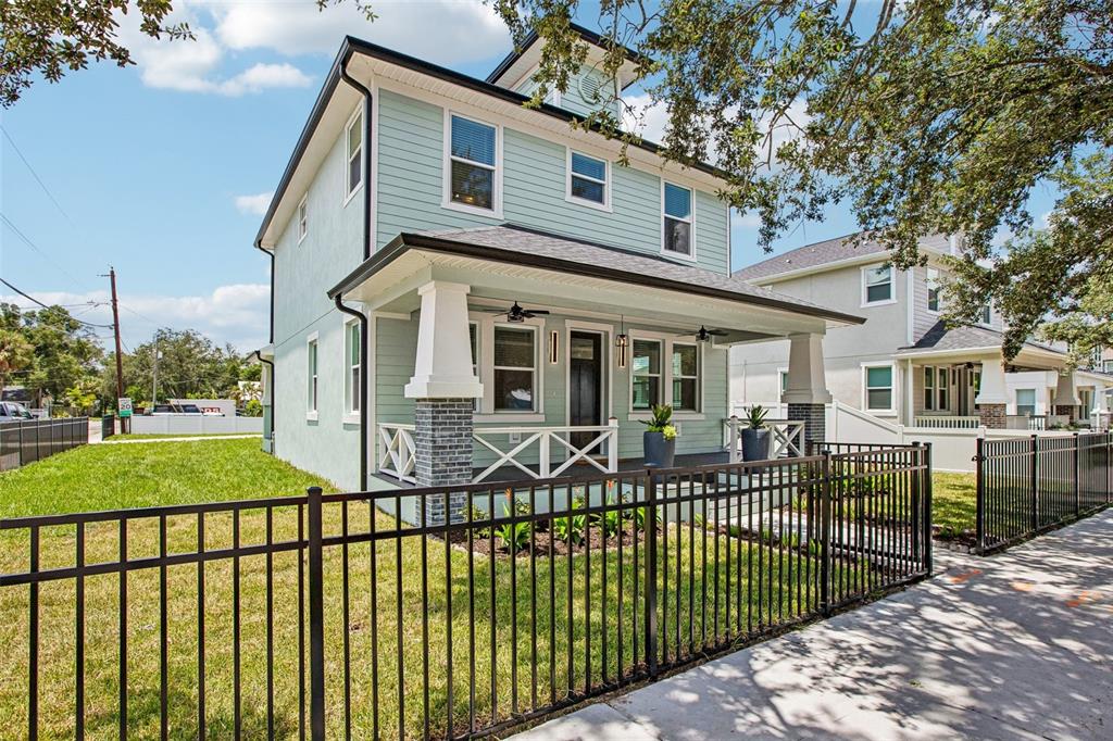 A light green two-story house with a front porch and black metal fence — 406 E CHELSEA STREET, TAMPA, FL
