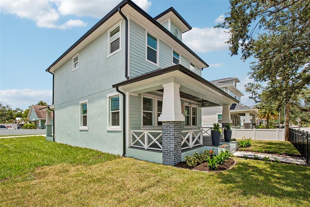 A two-story house with light green siding, a covered front porch, and a brick base — 406 E CHELSEA STREET, TAMPA, FL